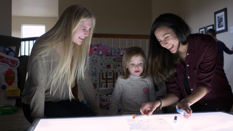 Researchers play with child over lighted table