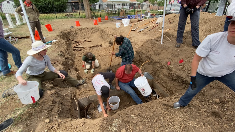 Archaeologists digging in a hole