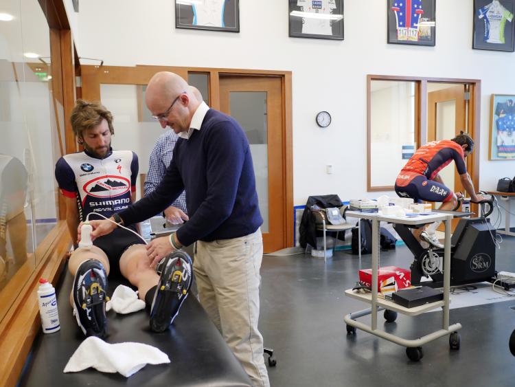 Inigo San Milan, director of the sports performance program at the CU Sports Medicine Center, uses a new hand-held ultrasound technology that enables trainers, athletes and physicians, for the first time, to measure glycogen levels inside muscle in real time on pro cyclist Chris Winn. (Photo by Glenn Asakawa/University of Colorado)