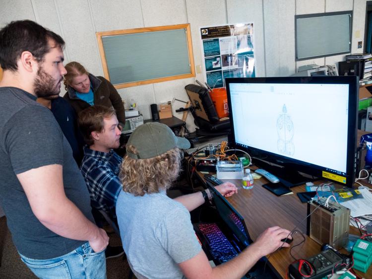 Engineering students gather round computer monitor