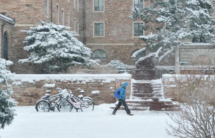 Student walking across campus in the snow.