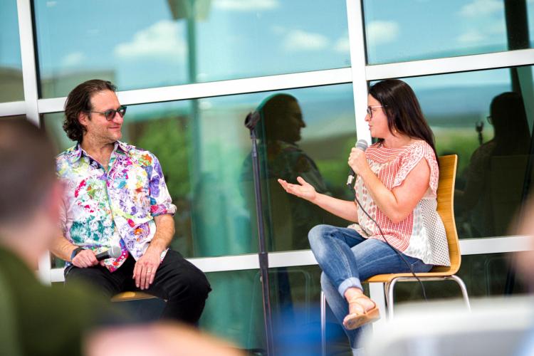 Delnaey Keating speaks into a microphone on an outdoor stage with Brad Feld