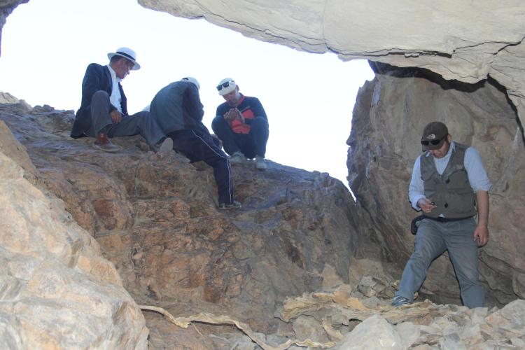 Four men explore the mouth of a cave