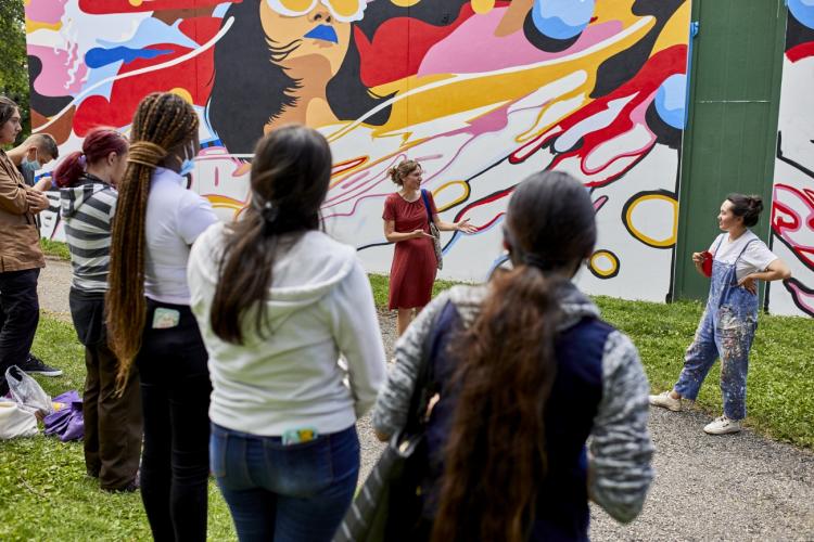 Cindy Regal talks to a group of women in front of a mural