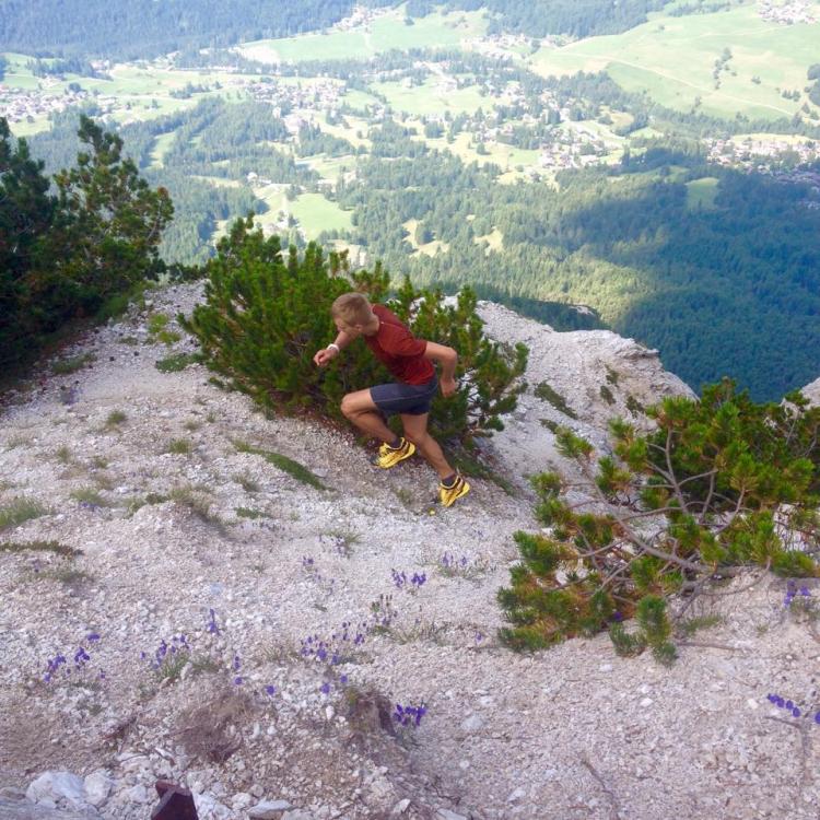 a male athlete runs uphill in mountainous terrain