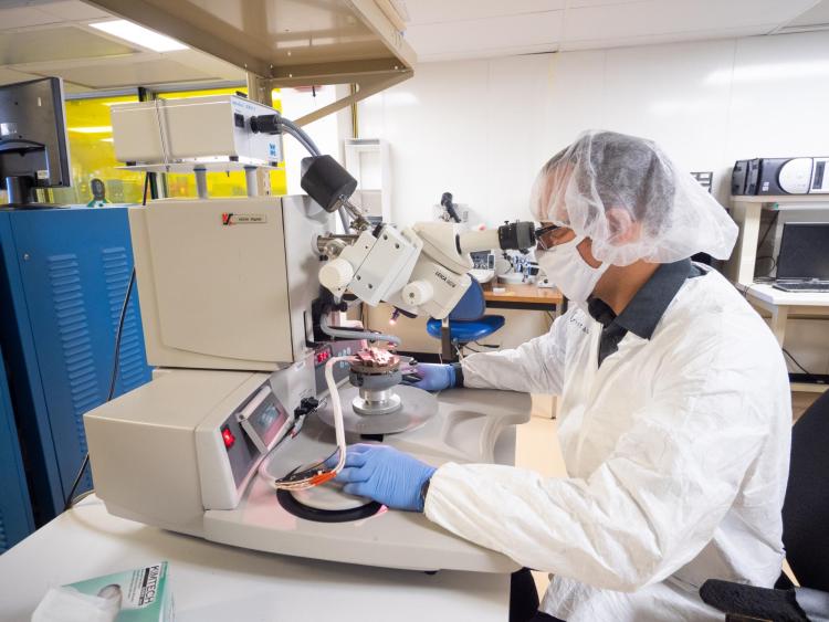 Person looking through lens of microscope