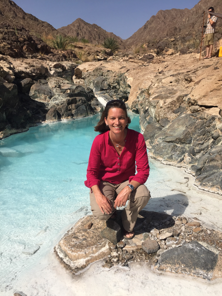 Alexis Templeton kneels on a rock in the middle of a spring