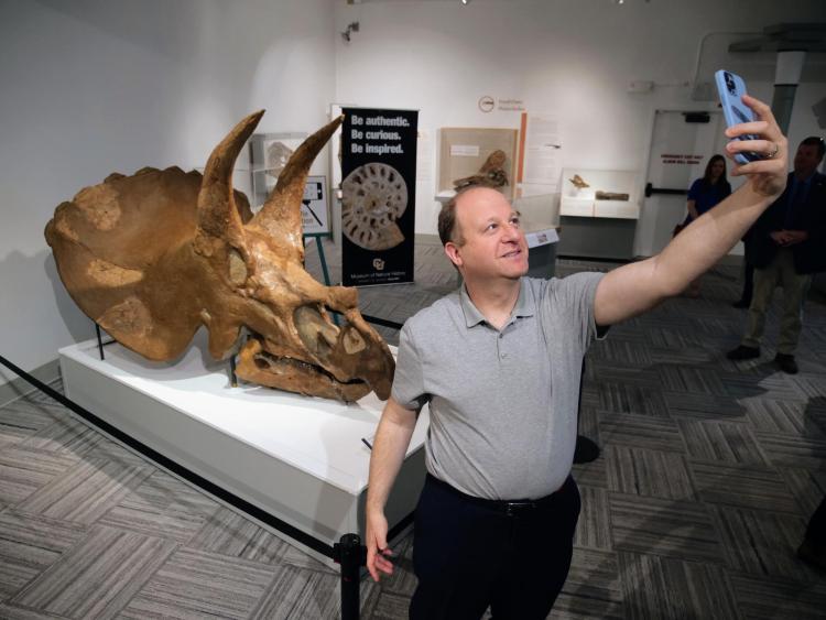 Gov. Polis takes a selfie with the Triceratops skull