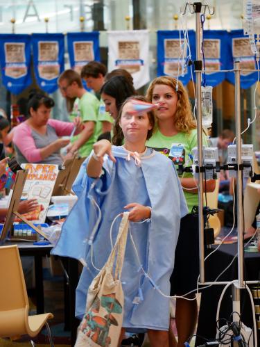 A CU student watches a STEAM Camp participant at Children's Hospital launch a paper airplane.