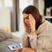 person with head in hands sitting on side of bed