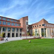 The CU Boulder Art Museum in the summer with people walking by, down the sidewalk.