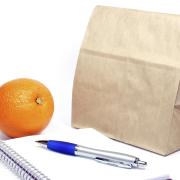Brown-bag lunch with an orange, notebook and pen