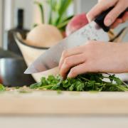 Person cutting up cilantro in kitchen