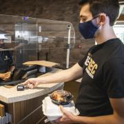 Student wearing mask swipes Buff OneCard in a dining hall