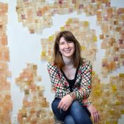 Ariana Kolins sits in front of a wall covered in used, empty tea bags