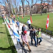 Students walk along sidewalk lined with international flags during the Conference on World Affairs