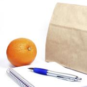 Brown-bag lunch with a notebook, pen and an orange