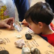 Child analyzes rocks under a magnifying glass