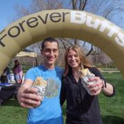 Two graduating students pose with free burritos in front of a Forever Buffs arch