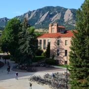Students walk past Hellems on their way to classes with the majestic Flatirons in the background