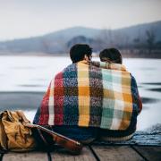 Couple sharing a blanket by the lake