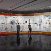 People stand, looking at an exhibit on a curved wall. 