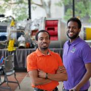 Yohannese Gebremedhin, right, and Arthur Antoine, left, stand in front of a model of a rocket in the engineering center on the University of Colorado Boulder campus.