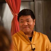 Orgyen Chowang Rinpoche sits in front of curtains