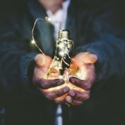 Person holding lightbulb with a string of LED lights