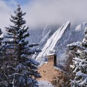 Top of a campus building with snowy Flatirons in the background