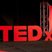 3D, red TEDx logo on stage, photo courtesy of TEDx Oakland University