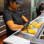 Dining employee prepares cheeseburgers at The Alley at Farrand