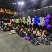 Group leaders hide behind the stage before leading admitted students and their parents to their respective areas of interest. Photo by Glenn Asakawa.