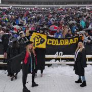 Graduates hold up a black and gold Colorado banner