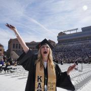 Graduate poses for a photo before the commencement ceremony at Folsom Field. Photo by Glenn Asakawa.