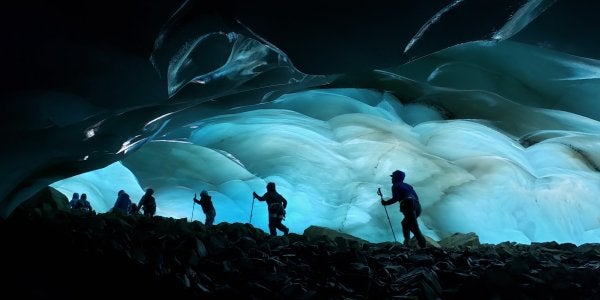 A photo of hikers at night in front of a cave of ice