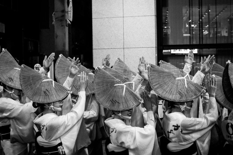 A black-and-white photo of dancers in tradtional Japanese dress and headpiece