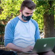 Student wearing mask using laptop outside