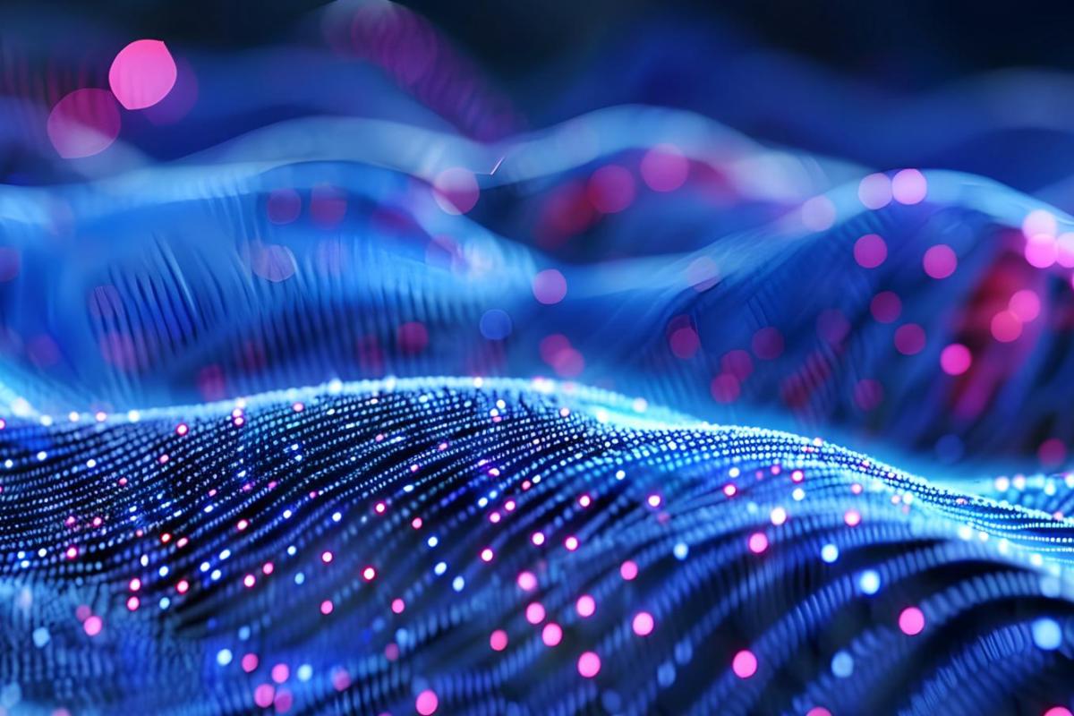 The image depicts a futuristic, wave-like surface covered with glowing dots of light in shades of blue and pink. These lights form a grid that undulates across the scene, suggesting the manipulation of electromagnetic waves or data signals. The background is soft, with blurred circular light patterns adding a sense of depth and motion. The overall effect is one of advanced technology and innovation, perhaps representing concepts in wave manipulation, metamataterials, or quantum computing.
