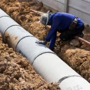 Worker laying pipe in a trench