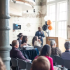 People in a modern industrialized space listen to a business presentation.