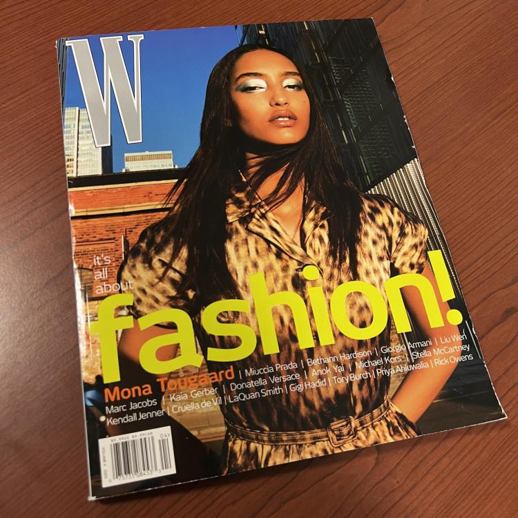 W Fashion magazine cover pictures a person with brown skin and dark brown hair posed in a city landscape with metallic eyeshadow and a leapord print short sleeve jump suit 