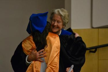 Dr. Annaleigh Curtis receiving her doctoral hood from Dr. Jaggar at graduation